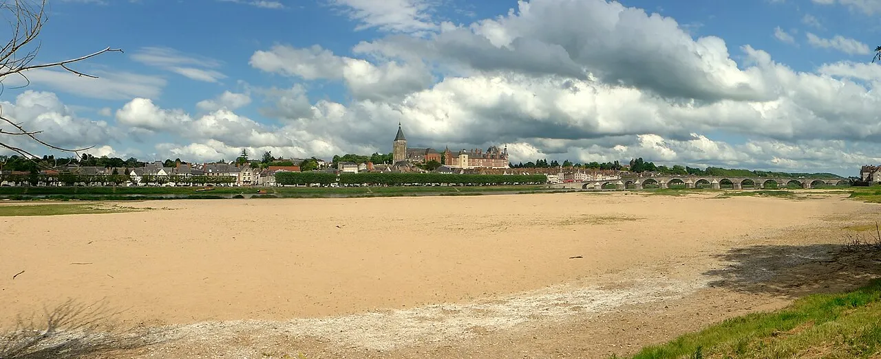 Dry riverbed with stone bridge and town spire
