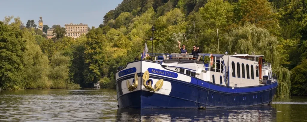 Magna Carta riverboat cruising past historic building
