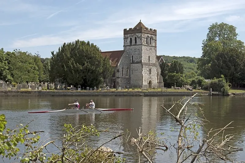 Rowers on river near historic stone church